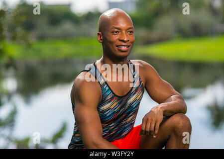 Happy young fitness model posing in the park. Young African American male model smiling off camera. Image lit with off camera flash Stock Photo