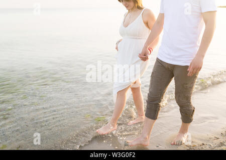 Couple holding hands walking romantic on beach on vacation travel holidays. Closeup of body and golden sand for copy space. Young loving couple Stock Photo