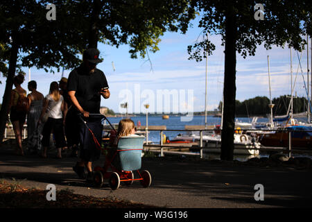 Man with a child in a stroller walking along Merihaka seaside during Kallio Block Party 2018 in Helsinki, Finland Stock Photo