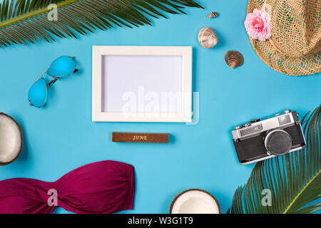 Photo frame, hat, camera, sunglasses, coconuts, on the blue background. Top view. Stock Photo