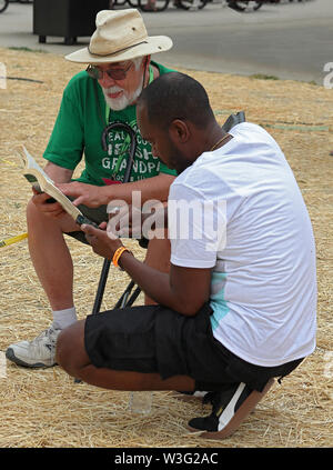 Littleton, Colorado - July 13, 2019: Two men, old and young, discussing a book on Colorado Irish festival. Stock Photo