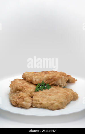 Close-up of a fish dish with three pieces of cod breaded with chinese parsley on a white background Stock Photo