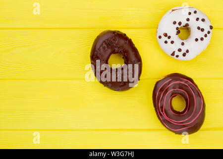 Three different donuts on yellow background. Stock Photo