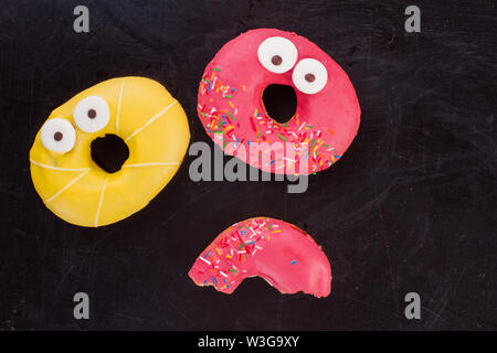 Two colorful donuts on dark background. Stock Photo