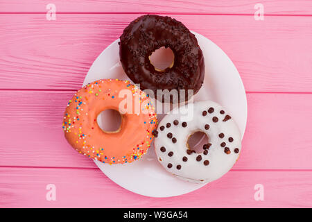 Three donuts on plate, top view. Stock Photo