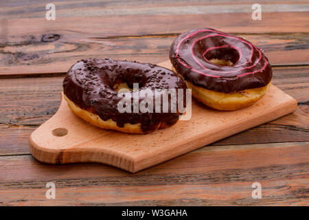 Two chocolate donuts on cutting board. Stock Photo