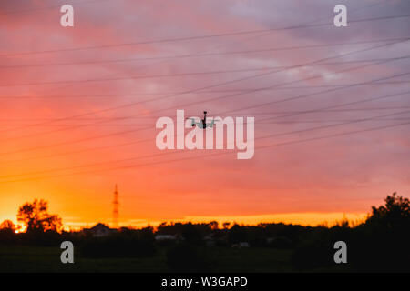 Custom made drone flying on sunset near power lines. Concept modeling, detection of obstacles Stock Photo