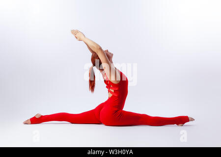 Beautiful slim woman in sports overalls  doing yoga, standing in an asana pose - twine arms over head on white  isolated background. The concept of sp Stock Photo
