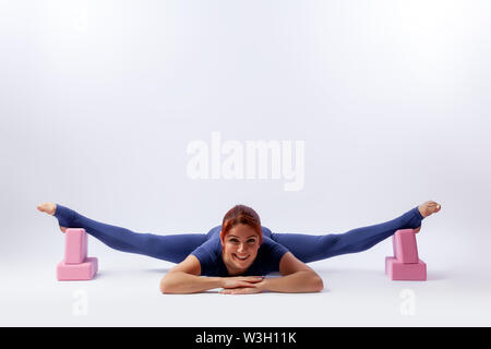 Beautiful slim woman in sports overalls  doing yoga, standing in an asana pose - twine  on white  isolated background. The concept of sports and medit Stock Photo