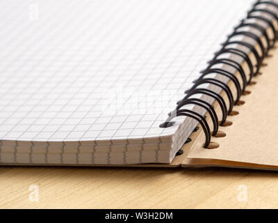 Notebook with checkered sheets on a wooden table. Side view Stock Photo