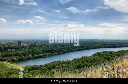 Beautiful natural scenery of river flowing in a green forest under a clear blue sky with some white clouds on the horizon Stock Photo