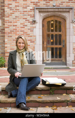 Beautiful, happy, smiling, female woman college university student studying using laptop computer on school campus Stock Photo