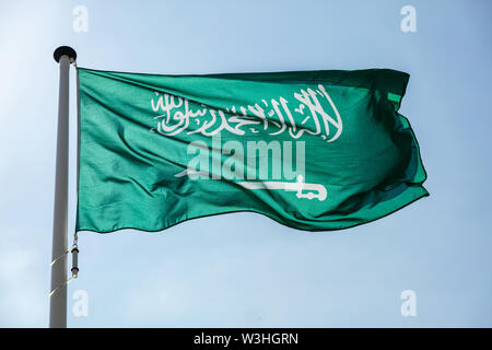 Saudi Arabia flag, National symbol waving against clear blue sky, sunny day Stock Photo