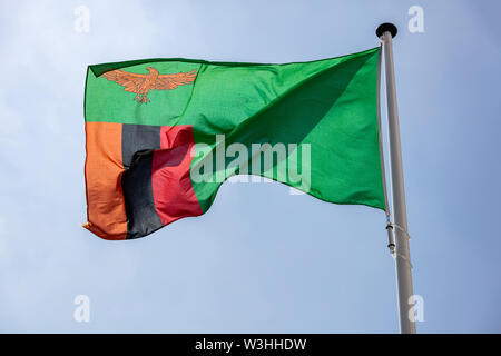 Zambia flag, National symbol waving against clear blue sky, sunny day Stock Photo