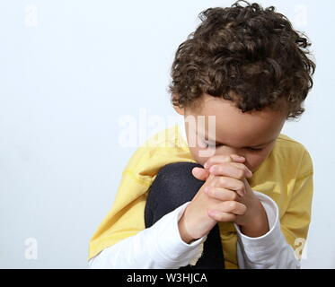 little boy praying to God and being religious stock image with hands held together praying in church on sunday stock photo Stock Photo