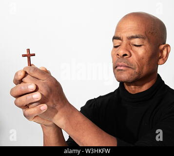 black man praying to god with cross and hands together Caribbean man praying with white background stock image stock photo