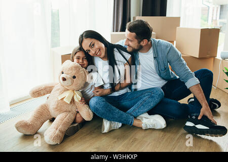 Happy couple with child while sitting at floor in new house Stock Photo