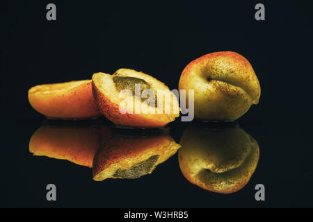 Beautiful two fresh apricots on a black glass table background. Stock Photo