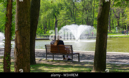 Debrecen Hungary 04 19 2019 young couple sitting on a bench and enjoying the nice weather in Debrecen in the Great Forest park Stock Photo