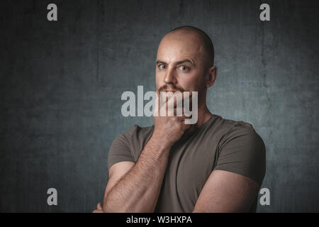 portrait of pensive caucasian man with t-shirt and dark background. Shot taken in the studio. Stock Photo