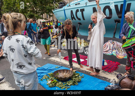 London, UK. 15th July, 2019. People bring water from across the country and pout it into a bowl. Extinction Rebellion begins another series of protests in five major cities against the criminal inaction by the government on climate and ecological collapse. The protesters brought a yacht named after Polly Higgins who fought for years for an Ecocide Law to the Royal Courts of Justice and continued her fight blocking the Strand all day with performances, discussions, speeches, music and ceremonies in front of the yacht. Credit: Peter Marshall/Alamy Live News Stock Photo