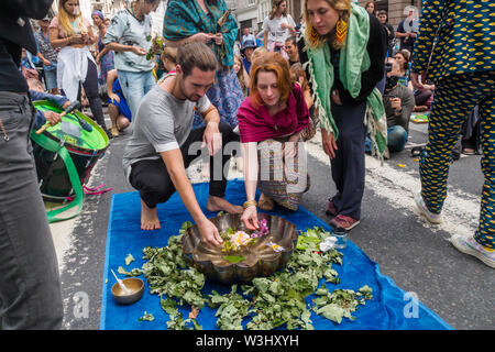 London, UK. 15th July, 2019. People add flowers to water from across the country in a ceremony against ecocide. Extinction Rebellion begins another series of protests in five major cities against the criminal inaction by the government on climate and ecological collapse. The protesters brought a yacht named after Polly Higgins who fought for years for an Ecocide Law to the Royal Courts of Justice and continued her fight blocking the Strand all day with performances, discussions, speeches, music and ceremonies in front of the yacht. Credit: Peter Marshall/Alamy Live News Stock Photo