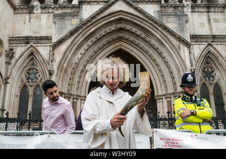 London, UK. 15th July 2019. A druid stands with a horn filled with water from across the countryin front of the courts in a ceremony against ecocide. Extinction Rebellion begins another series of protests in five major cities against the criminal inaction by the government on climate and ecological collapse. The protesters brought a yacht named after Polly Higgins who fought for years for an Ecocide Law to the Royal Courts of Justice and continued her fight blocking the Strand all day with performances, discussions, speeches, music and ceremonies in front of the yacht. Peter Marshall/Alamy Liv Stock Photo