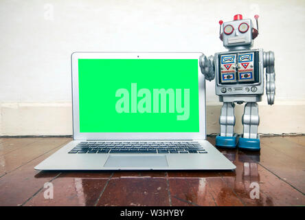 big silver robot gives a presentation on a laptop Stock Photo
