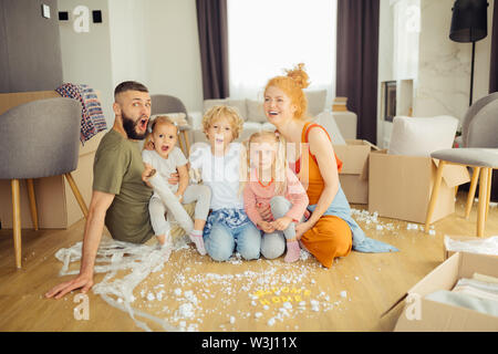 New home. Positive delighted family sitting together in the middle of the room while moving to a new house Stock Photo