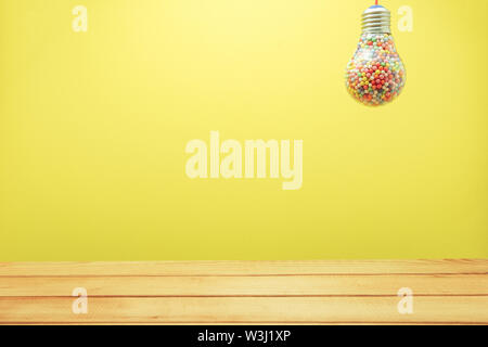Creative lightbulb filled with multi colored ball on a Yellow background behind and red wooden floor or table down. Best idea concept. Stock Photo