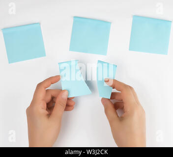 lot of blue stickers on a white background and two female hands, conceptual background Stock Photo