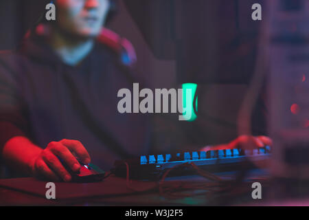 Close-up of busy man sitting at table with wires and using computer mouse while playing video game Stock Photo