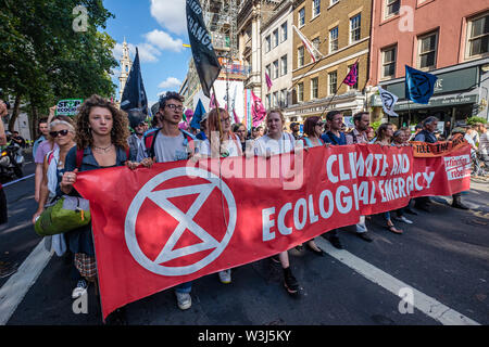 London, UK. 15th July 2019. The banner at the front of the Extinction Rebellion march from the Royal Courts of Justice to their site for the next three days at Waterloo Millennium Green. As well as protesters with banners, there was a giant pink dodo, and at the rear of the procession the yacht Polly Higgins, named for the environmental lawyer who fought for years for a law against ecocide and died this April. Credit: Peter Marshall/Alamy Live News Stock Photo