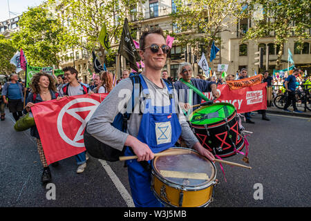 London, UK. 15th July 2019. Drummers at the front of the Extinction Rebellion march from the Royal Courts of Justice to their site for the next three days at Waterloo Millennium Green. As well as protesters with banners, there was a giant pink dodo, and at the rear of the procession the yacht Polly Higgins, named for the environmental lawyer who fought for years for a law against ecocide and died this April. Credit: Peter Marshall/Alamy Live News Stock Photo