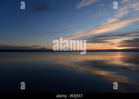 Sunlight at sunset from clouds on the horizon over water Stock Photo