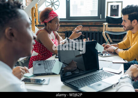 A team of young people of different nationalities discusses the work on the project in the office. Stock Photo