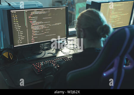 Rear view of concentrated software engineer sitting at table and composing app script while working in programming company Stock Photo