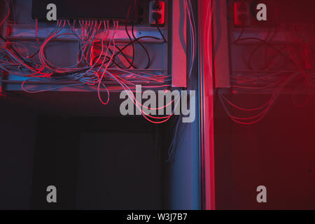 Close-up of network hardware hub with cables plugged into socket placed on wall in dark server room Stock Photo
