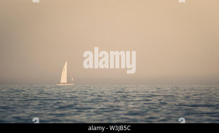 Distant sailing boat with German flag sails in Irish sea. Stock Photo