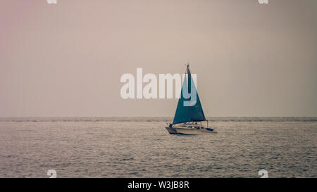 Sailing catamaran heading to safe harbor in pre-storm conditions. Stock Photo
