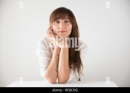 Portrait of a beautiful brunette caucasian woman wearing white against a white background Stock Photo