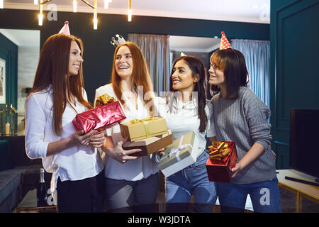 Group of cheerful beautiful women standing together with gifts while having birthday party Stock Photo