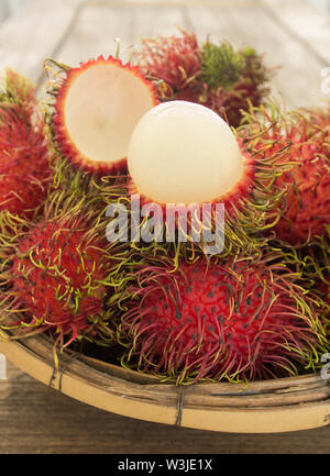 rambutan asian fruit in basket on wooden table.