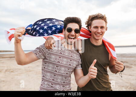 Happy friends spending time at the beach, holding american flag Stock Photo