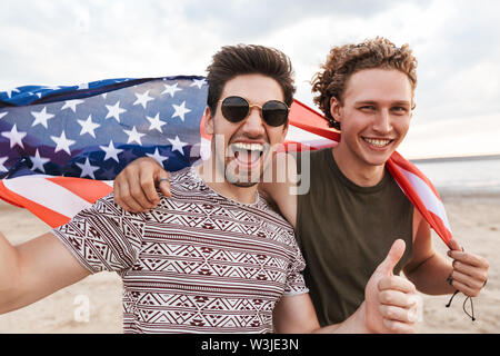 Happy friends spending time at the beach, holding american flag Stock Photo