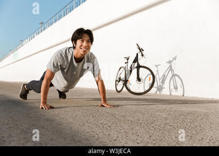 Young fit man bicyclist working out oudoors, doing push-ups Stock Photo