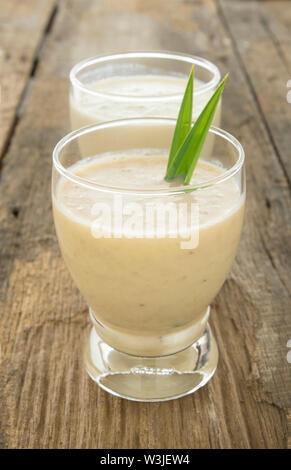 Banana smoothie on a wooden table with natural light. Stock Photo