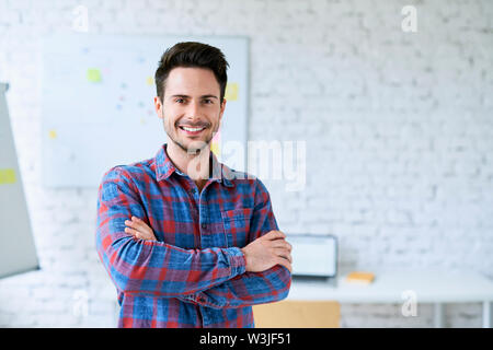 Portrait of successful programmer, web designer standing in start-up office Stock Photo