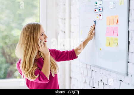 Female web developer discussing web site wireframe on the phone Stock Photo