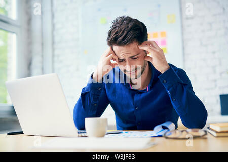 Stressed man in office looking on documents Stock Photo